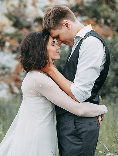 A couple stands closely in an embrace outdoors, gently touching foreheads, in California - wedding photography by Leah Marie Photography