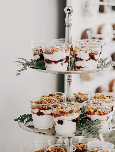 Individual parfait cups with layers of yogurt, granola, and fruit are arranged, in California - wedding photography by Leah Marie Photography