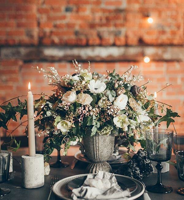 A rustic wedding tablescape features a floral arrangement in a stone urn, in California - wedding photography by Leah Marie Photography